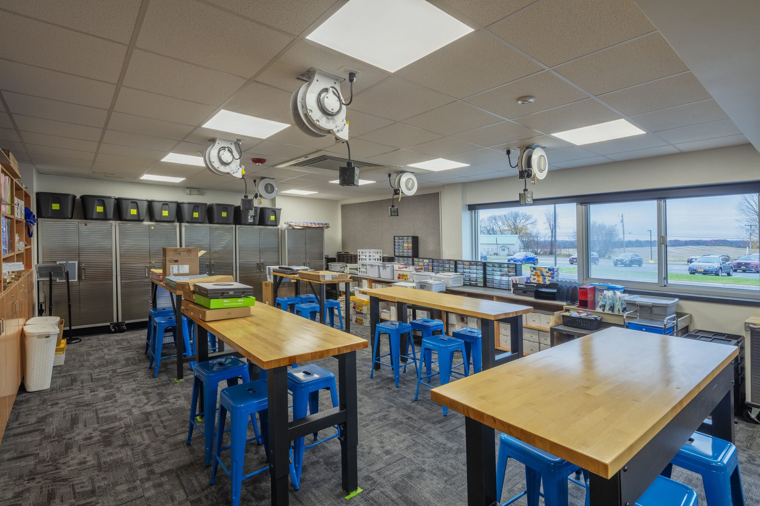 Modern school art classroom with tables and storage shelves.